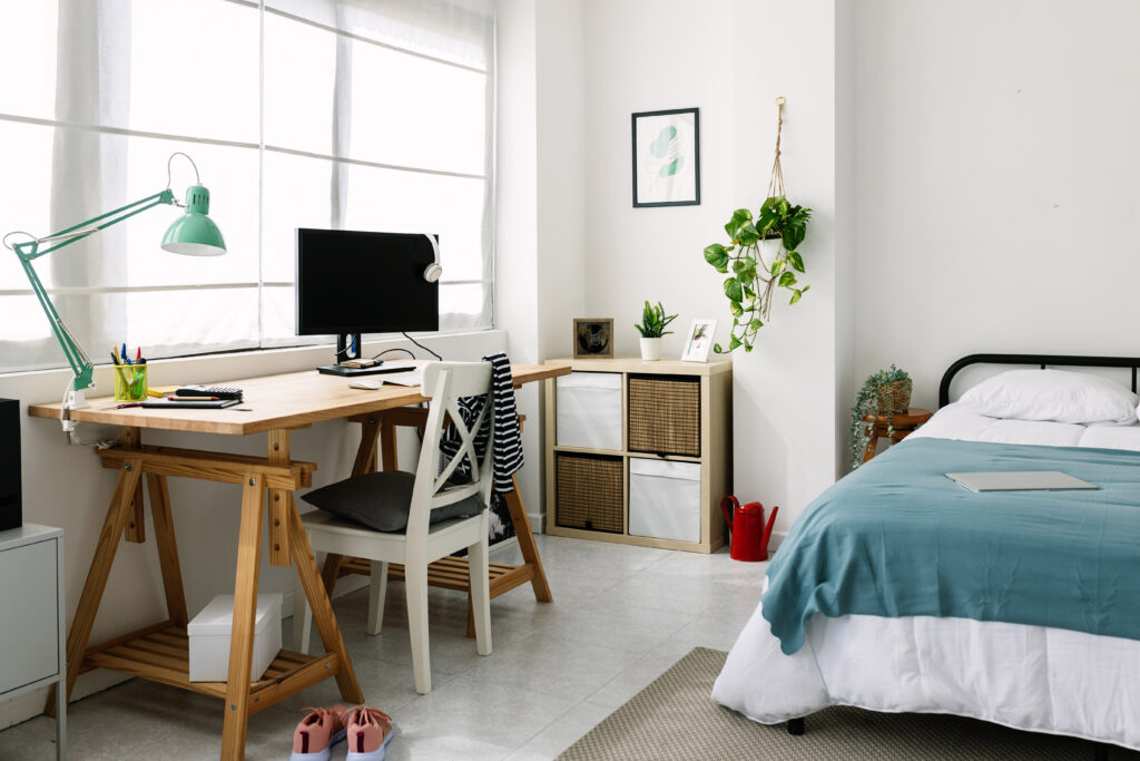 Cozy interior millennial college student room staged with bed, laptop and desk